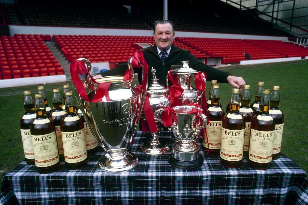 LIVERPOOL. ENGLAND. LFC manager Bob Paisley stands on the Anfield pitch, proudly displaying his haul from the 1980-81 season: The European Cup (v Real Madrid in final), League Cup (v West Ham in final), Liverpool Senior Cup (v South Liveprool in final), Central league Trophy (reserves) and 16 bottles of Bell's whiskey as manager of the month and other special season awards. (Getty Images)